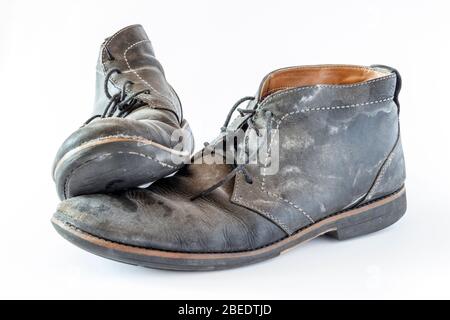 Un paio di scarpe in pelle nera sporca e logore isolate su uno sfondo bianco Foto Stock