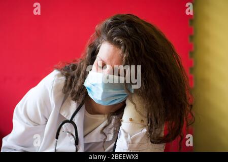 Stanco medico femmina che prende un pisolino su un tavolo con maschera ritratto da primo piano. Assistenza sanitaria, chirurgia. Foto Stock