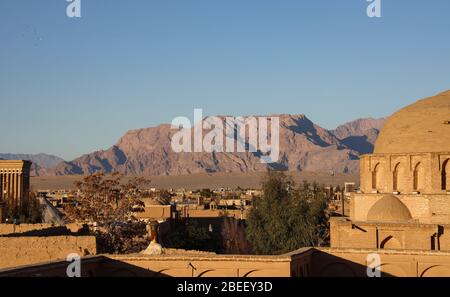 Vista sui tetti al tramonto con montagne sullo sfondo, Yazd, Yazd Province, Iran, Persia, Medio Oriente. Foto Stock