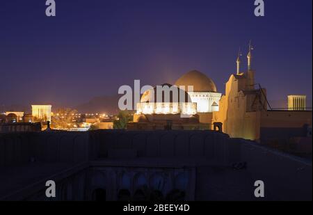 Vista dei tetti con i windcatchers, i wind tower (badgirs) e Jameh Masjid, (Moschea del venerdì) di notte a Yazd, provincia di Yazd, Iran, Persia, Medio Oriente. Foto Stock