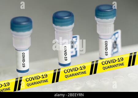 Nastro segnaletico giallo coronavirus contro contenitori piccoli con coperchi blu contrassegnati con COVID-19 e codice QR. Ricerca medica. COVID-19 pandemico. Primo piano Foto Stock