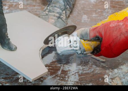 L'uomo lavoratore professionale piastrella di taglio con sega circolare su elettrico ristrutturazione bagno Foto Stock