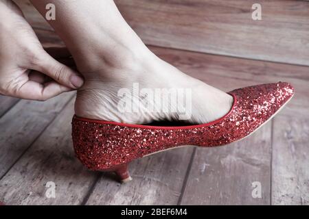 donna massaggiando il suo piede doloroso sul pavimento. Foto Stock