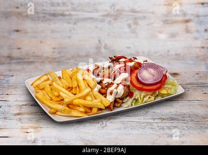 Gyros souvlaki e patatine fritte in bianco piatto su tavolo di legno Foto Stock