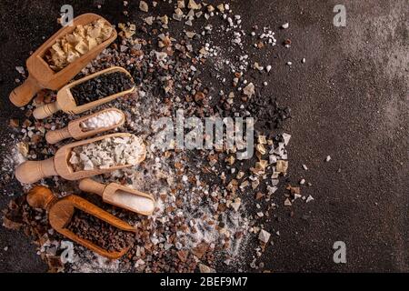 Cristalli di sale gourmet in scoop su sfondo scuro Foto Stock