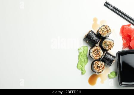 Deliziosi panini di sushi, salse e bacchette su sfondo bianco, spazio per il testo Foto Stock
