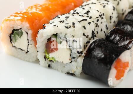 Deliziosi panini di sushi sullo sfondo bianco della ciotola, primo piano. Cucina giapponese Foto Stock