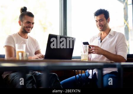 Due uomini felici come amici che lavorano insieme al bar Foto Stock