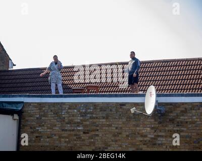 Londra. Leyton. REGNO UNITO. Il 10 aprile 2020. Vista della coppia che si è accesa il bel tempo sul tetto del loro appartamento durante il Lockdown Covid-19. Foto Stock