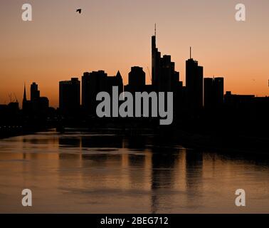 13 aprile 2020, Hessen, Francoforte sul meno: I grattacieli della città bancaria appaiono come silhouette al tramonto. Foto: Arne Dedert/dpa Foto Stock