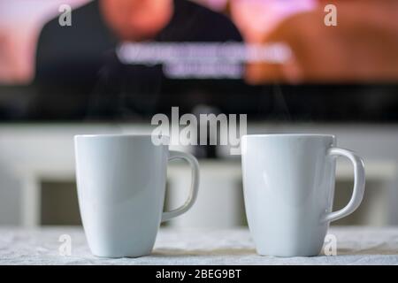 Tazze da caffè con schermo televisivo con film e sottotitoli in background. Foto Stock