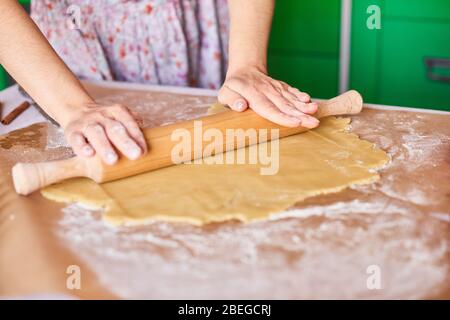 Mani lavorando con preparazione di pasta ricetta del pane. Mani femminili rendendo la pasta per pizza. Donna con le mani in mano il rotolo di pasta. Madre rotoli pasta sul kitche Foto Stock