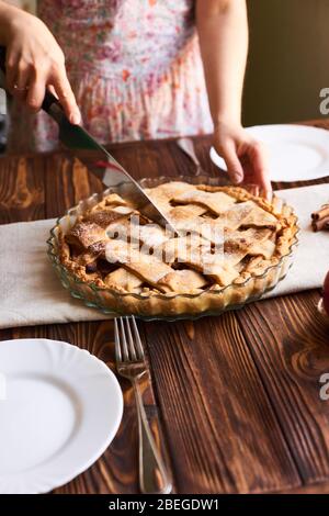 Donna che mette deliziosa torta americana sul tavolo. Primo piano mani donna taglio di una torta di mele fatta in casa. Piastre bianche sul tavolo Foto Stock