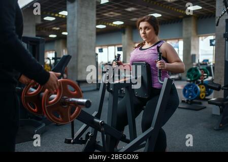 Donna in sovrappeso su macchina ginnica in palestra Foto Stock