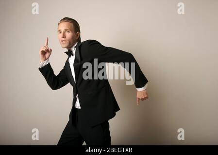 Fresco giovane uomo in completo danzare tuxedo con gesti sciocco Foto Stock