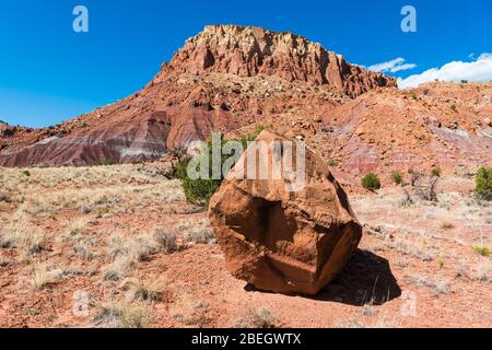 Grande masso in un paesaggio desertico con una mesa colorata sullo sfondo vicino Abiquiu, New Mexico Foto Stock