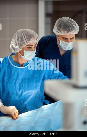 Le fotografie dei medici in maschere protettive e camici da laboratorio lavorano intensivamente in terapia intensiva. Reparto rianimazione, salvavita, polmonite, Covid Foto Stock