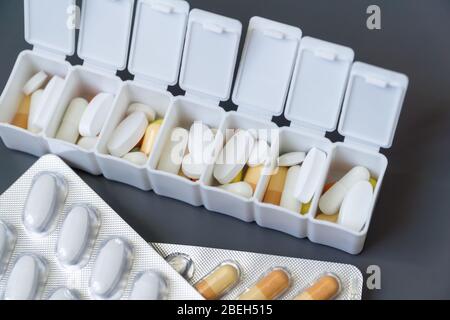 Pillole, compresse e capsule di medicina diversi colori in confezione per pillole su sfondo grigio, fuoco selettivo. Assistenza sanitaria. Foto Stock
