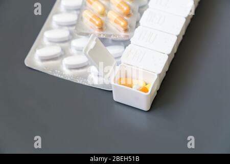 Pillole, compresse e capsule di medicina diversi colori in confezione per pillole su sfondo grigio, fuoco selettivo. Assistenza sanitaria. Foto Stock