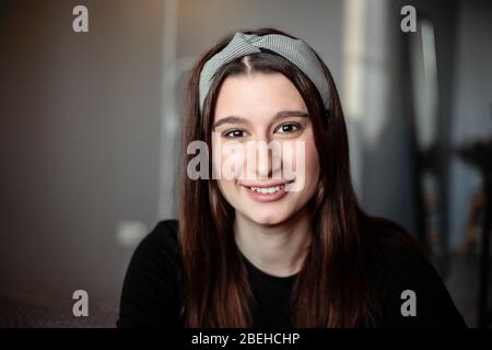 Una giovane bella ragazza è in un appartamento durante l'isolamento. È vestita con abiti neri e una bandana sulla testa Foto Stock