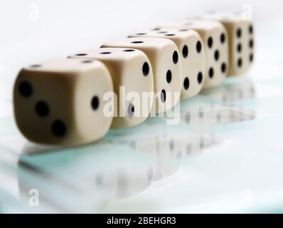 Una fila di sei dadi - che mostra i numeri sequenziali 1 - 6, seduti su una superficie riflettente. Foto Stock