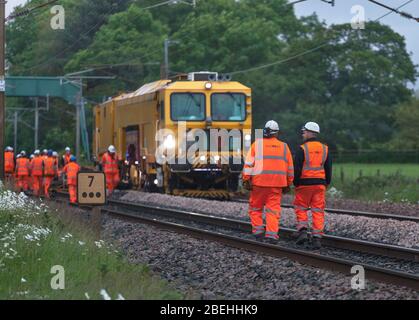 Macchina per la costipatura con imprese ferroviarie per la zavorra di imballaggio della rete ferroviaria sotto il nuovo binario a Brock, a nord di Preston, sulla linea principale della costa occidentale Foto Stock