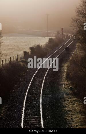 Linea ferroviaria rurale a binario singolo in una mattinata misteriosa a Park South sulla linea ferroviaria della costa Cumbria Foto Stock