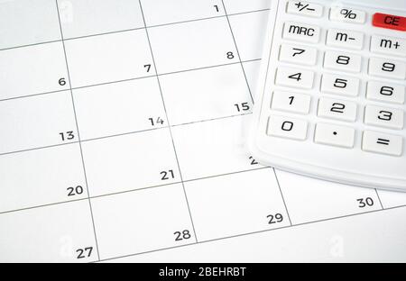 Un concetto finanziario con una calcolatrice sul calendario. Foto Stock