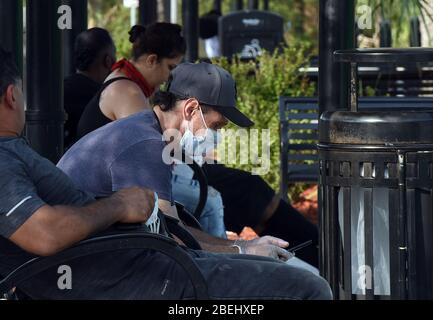 Kissimmee, Stati Uniti. 13 Aprile 2020. 13 aprile 2020 - Kissimmee, Florida, Stati Uniti - UN uomo indossa una maschera facciale mentre aspetta un autobus a Kissimmee, Florida il 13 aprile 2020, il primo giorno che i funzionari locali nella contea di Osceola, Florida vicino Orlando ha reso obbligatorio l'uso di rivestimenti del viso in pubblico nel tentativo di frenare la diffusione della pandemia COVID-19. Credit: Paul Hennessy/Alamy Live News Foto Stock