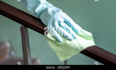 Vista in primo piano della mano di una donna con un panno antibatterico bagnato per disinfettare la ringhiera sulla gabbia volante. Foto Stock