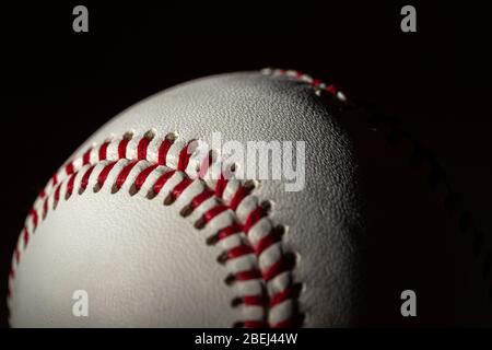 Un baseball bianco in pelle su sfondo nero Foto Stock