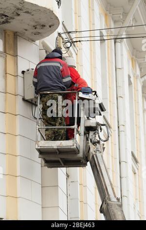 Vladivostok, Russia - 26 marzo 2020: Gli elettricisti lavorano in altezza in un cesto di una piattaforma di sollevamento idraulica. Foto Stock