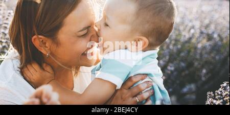 Affascinante madre caucasica e suo figlio che gioca in un campo di lavanda mentre sorridono divertente Foto Stock