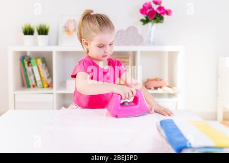 Bambina gioca con il giocattolo di ferro e asse da stiro Foto