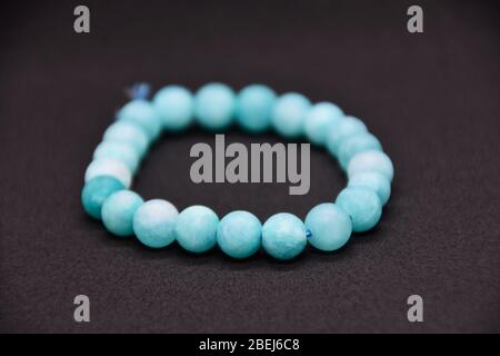 Bracciale fatto in casa con perle di pietra semi-preziosa blu naturale su sfondo nero Foto Stock
