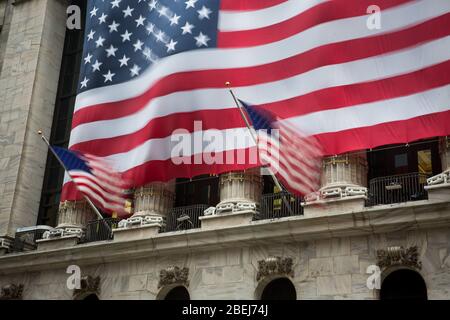 New York, Stati Uniti. 13 Aprile 2020. Le bandiere nazionali degli Stati Uniti sono soffiate da raffiche di vento davanti alla Borsa di New York (NYSE) a New York, negli Stati Uniti, 13 aprile 2020. Il vento e la pioggia forti hanno colpito New York il lunedì. Credit: Michael Nagle/Xinhua/Alamy Live News Foto Stock