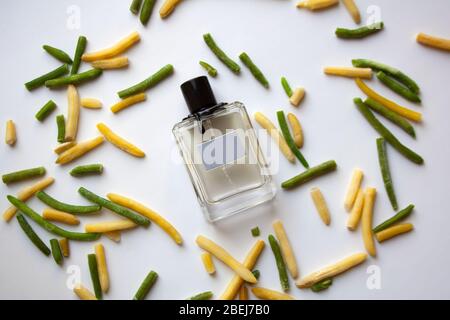 Bottiglia di vetro profumata con baccelli di fagioli verdi e gialli su sfondo bianco Foto Stock