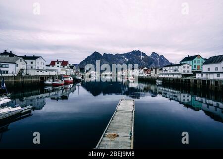 porto di henningsvaer con barche sul lato e montagna sullo sfondo Foto Stock
