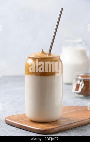 Dalgona caffè in vetro su grigio. Caffè espresso in latte con schiuma di caffè istantaneo. Inquadratura verticale. Bevanda creata durante la quarantena Foto Stock