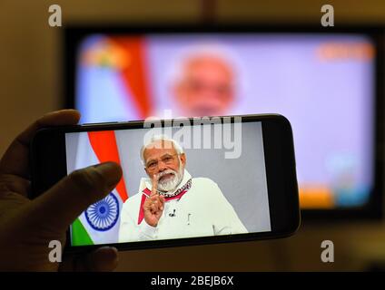 Kolkata, India. 14 Aprile 2020. In questa illustrazione della foto, il primo ministro indiano Narendra modi visto su uno smartphone e schermo che annuncia l'estensione del blocco fino al 3 maggio come misura preventiva contro la diffusione di Coronavirus.India ha confermato 10,200 casi di coronavirus e 330 morti. Credit: SOPA Images Limited/Alamy Live News Foto Stock