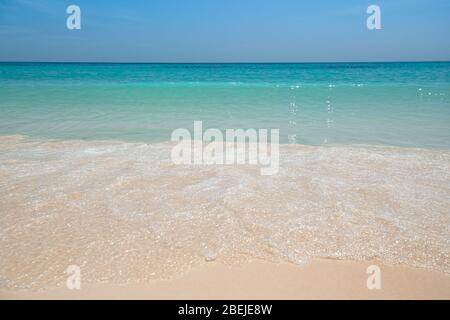 Mare tropicale con bella acqua acquamarina e onda di schiuma bianca che si rompe su spiaggia di sabbia fine giallo. Fondo marino. Thailandia Foto Stock