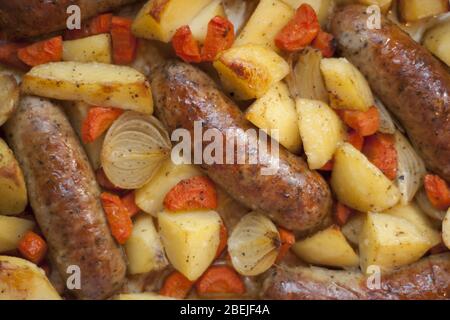 OPIS: Salsiccia al forno con patate, carote, cipolle e altre verdure come piatto semplice e veloce per tutta la famiglia. Foto Stock