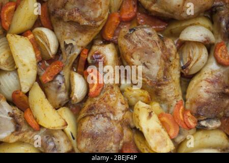 Cosce di pollo al forno con carote, cipolle, patate e aglio. Foto Stock