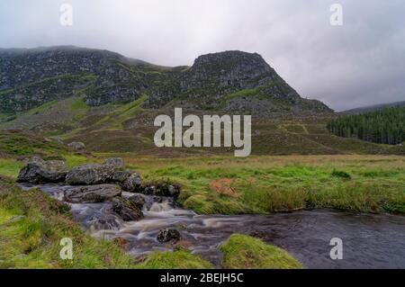 Un piccolo fiume che scorre attraverso Corrie Fee, con nuvola bassa e nebbia mattutina che copre le colline. Foto Stock