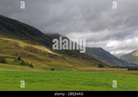 Il sole che attraversa il Dark Cloud Layer e sulle pendici ombreggiate dei lati della Valle di Glen Clova in una mattinata di agosto, Foto Stock