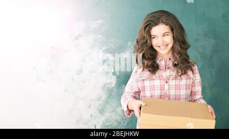 Ragazza giovane con scatola di consegna. Roba felice di trasferimento del bambino. Regalo per posta Foto Stock