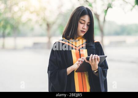 Giovane affascinante asiatico gradi feemale cerebrare la sua laurea dopo aver conseguito il diploma di laurea nel giorno di inizio. Congratulazioni per Edu Foto Stock