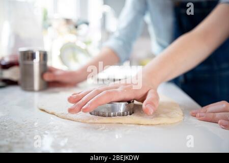 Primo piano di Madre e figlia utilizzando Pasticceria Cutter cottura in cucina a casa insieme Foto Stock