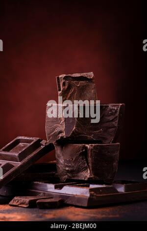 in primo piano accatastati pezzi di cioccolato fondente cosparsi di cacao in polvere. Foto Stock