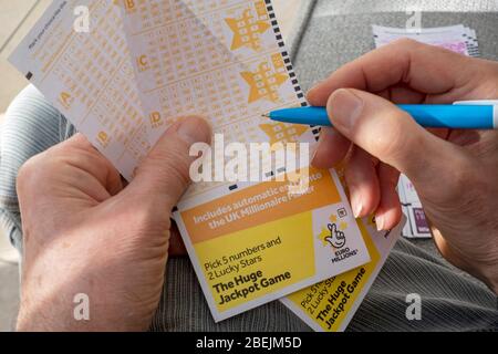 Primo piano di persona uomo che tiene la mano compilando il gioco del jackpot EuroMillions lotto lotteria modulo di biglietto Inghilterra Regno Unito Regno Unito Gran Bretagna Gran Bretagna Foto Stock
